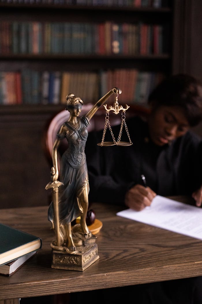 why-choose-us Close-up of Lady Justice figurine on a lawyer's desk with books and documents.